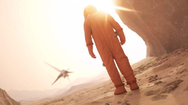 Ein Astronaut steht auf der Marsoberfläche und schaut einem startenden Raumschiff hinterher.